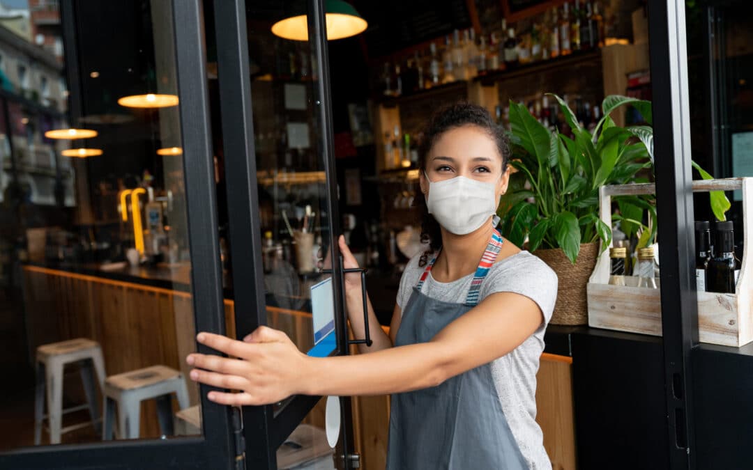 Happy business owner opening the door at a cafe wearing a facemask stock photo